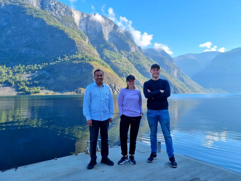 Tre forskarar, middelaldrande mann og to yngre - står i fjordlandskap