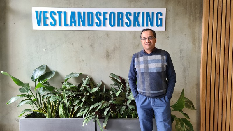 mann ved vestlandsforsking sitt skilt, planter bak