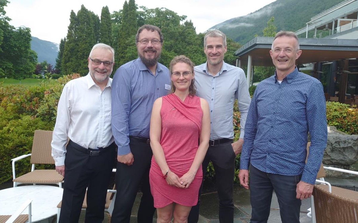 forskarar i fine klede framfor eit hotell