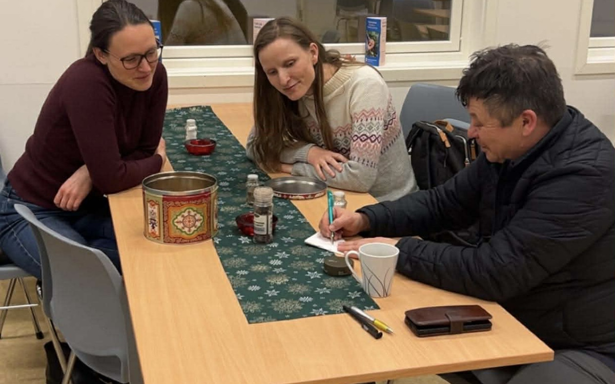 tre personar ser på eit ark der ein forklarer og teiknar