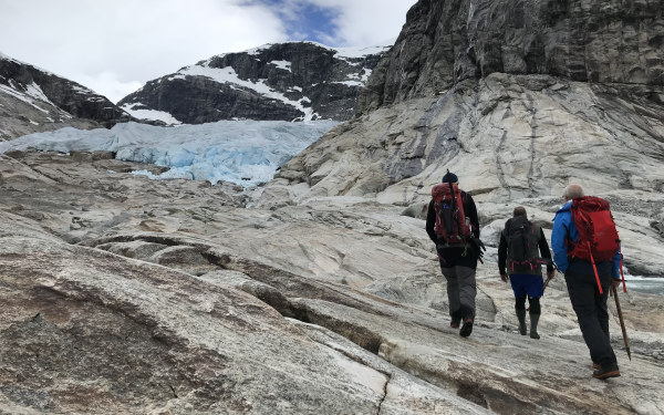 Isbre i bakgrunnen, folk på veg opp til isen på berget i turklede