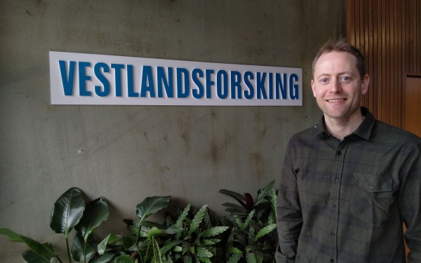 mann på 40 framfor skilt med logoen til Vestlandsforsking