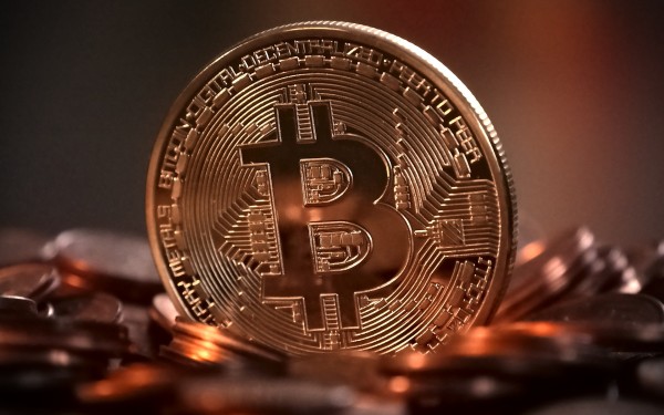Gullmynt med Bitcoin-symbol blant andre myntar