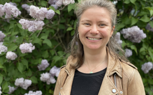 Alexandra - kvinneleg forskar - framfor blomstrande busk