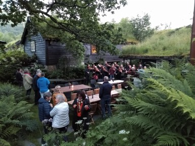 Mennesker ute på bakken foran gamle bygg