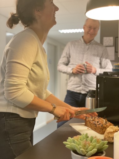 Kvinne skjer banankake og ler mens mann står i bakgrunnen og smiler